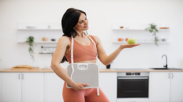 Health coach with measuring tape, scales and apple at home