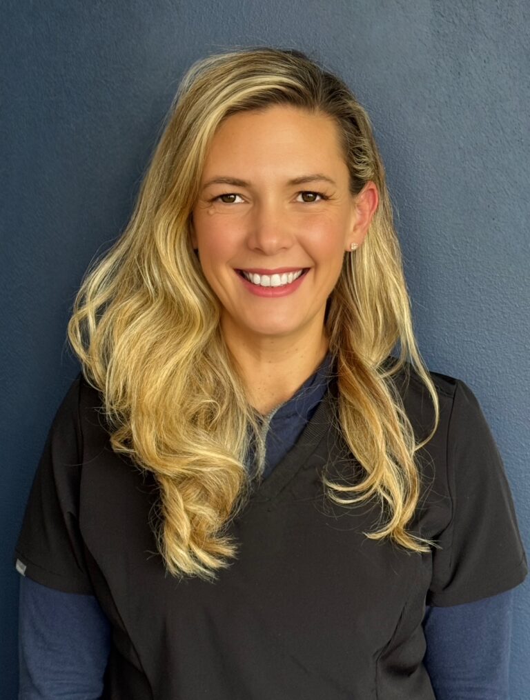 photo of blond health coach in blue scrubs smiling for the camera