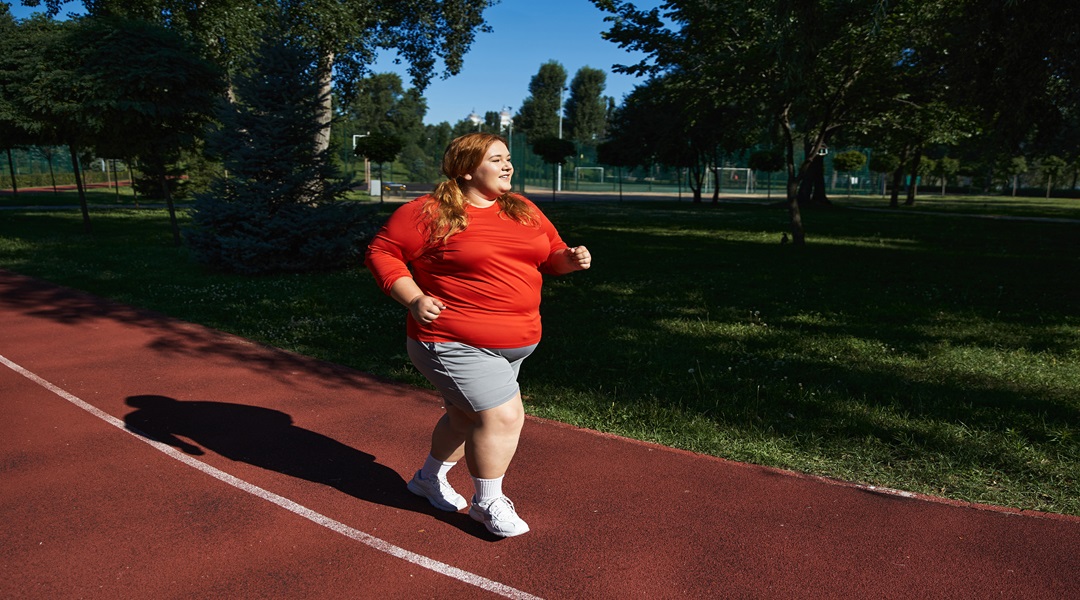 A joyful woman enjoys jogging outdoors in a vibrant park setting.