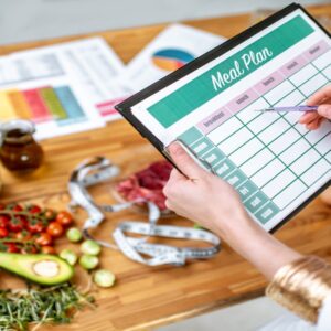 Writing a diet plan on the table full of healthy food