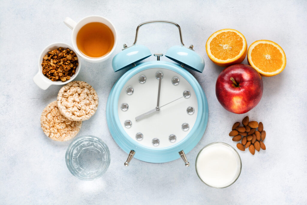 Concept of proper portioned nutrition for health calculated by the clock. Group useful breakfast coffee, tea, fruits, oats, nuts, milk, water, muesli. Background Circle Top view