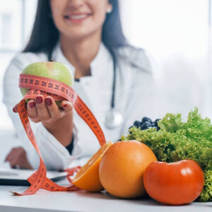 Doctor holds out a measuring tape next to vegetables.