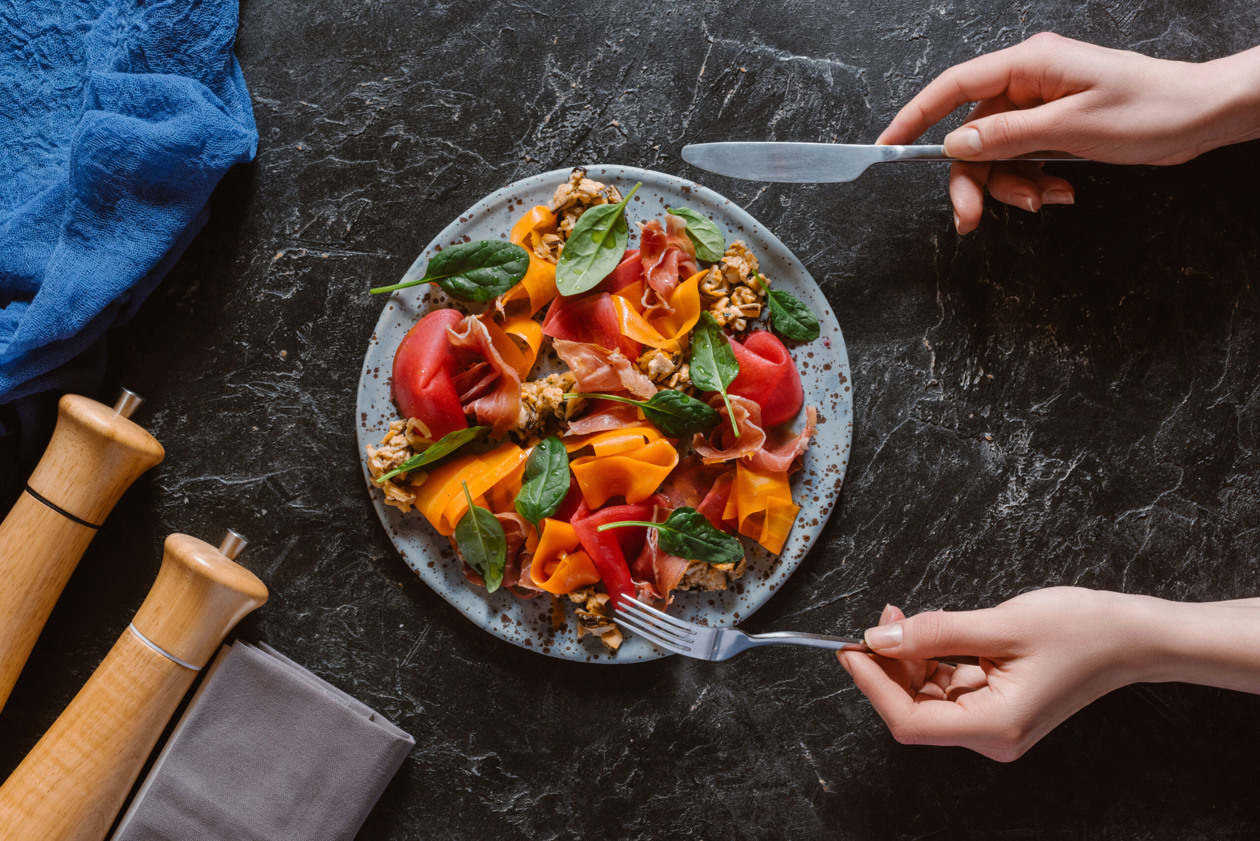 partial top view of person eating delicious salad with mussels, vegetables and jamon