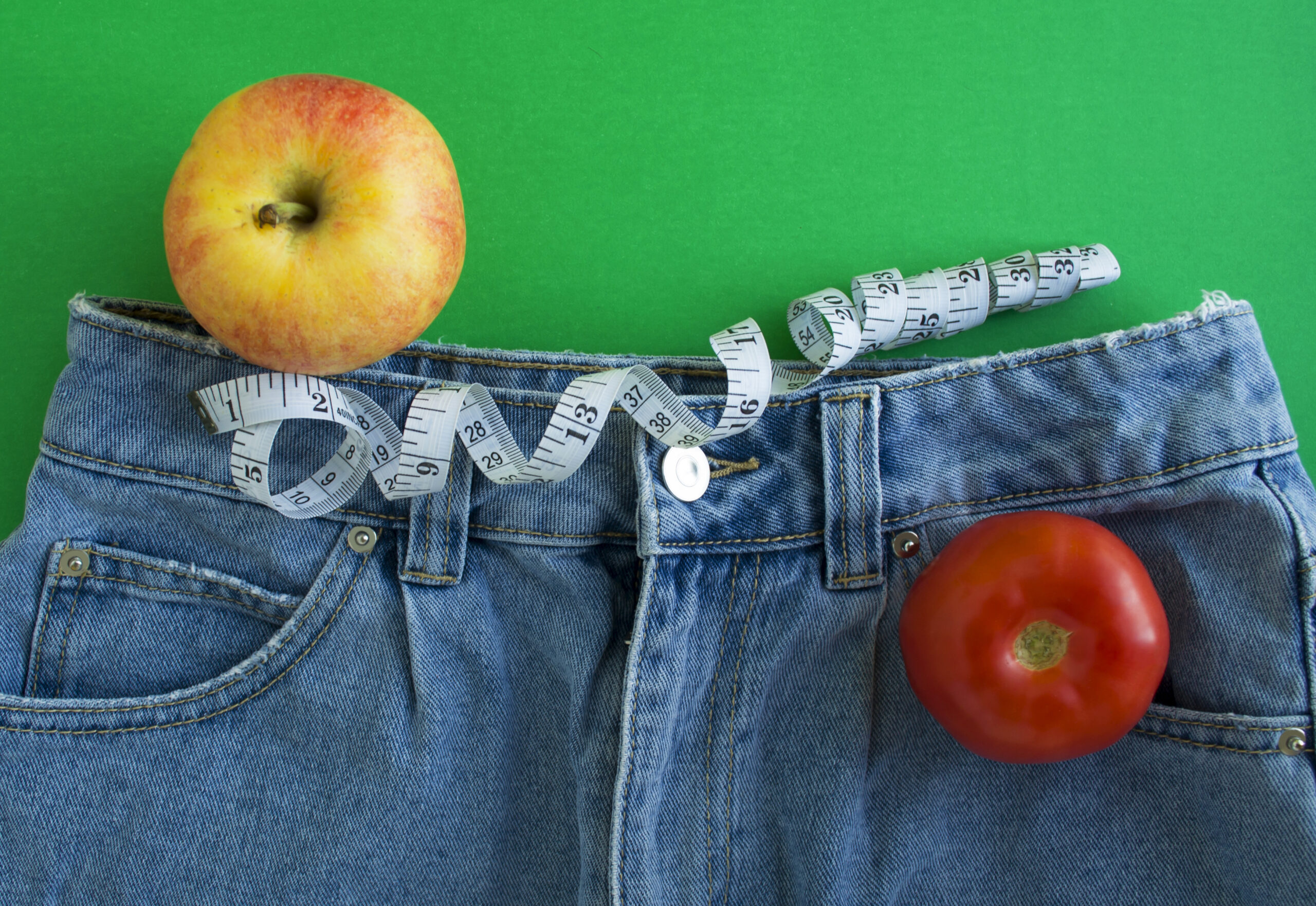 jeans next to 2 apples and a tape measure