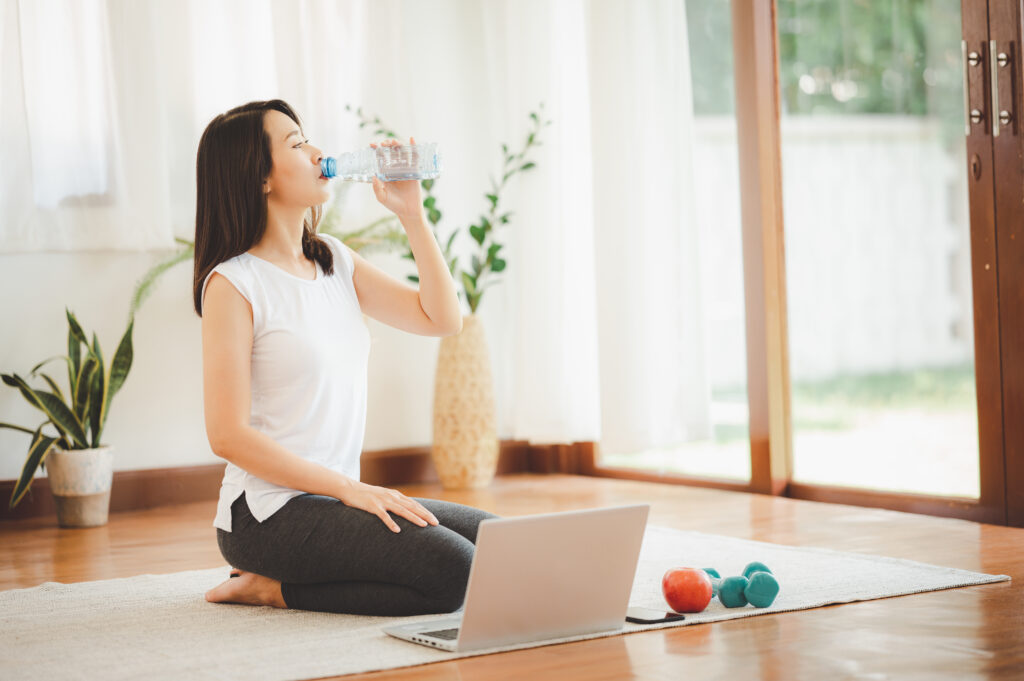 woman drinking water while doing virtual workout